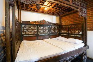 a bedroom with an old wooden bed with white sheets at Griya Gribig Guest House Mitra RedDoorz in Malang