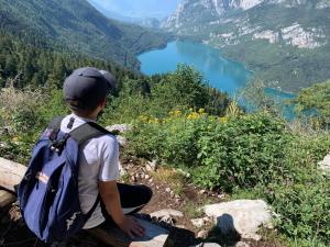 a person with a backpack sitting on a rock looking at a lake at Appartamento Family Park2 in Andalo