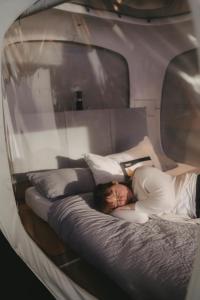 a woman is laying on a bed in a mirror at One Night in a Museum - LUNA Sleep Cube in Lüneburg