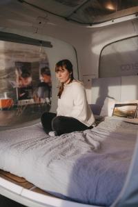 a woman is sitting on a bed in a camper at One Night in a Museum - LUNA Sleep Cube in Lüneburg