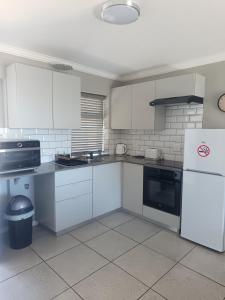 a kitchen with white cabinets and a white refrigerator at Millennial Arch in Langebaan