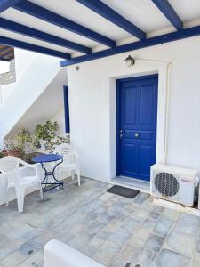 a blue door on a white wall with a table and chairs at Calm Paros in Logaras