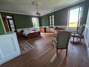 a living room with green walls and a table and chairs at Domaine de Lasserre in Lupiac