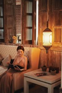 a woman sitting on a couch reading a book at Sheraton Sanya Yalong Bay Resort in Sanya