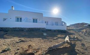a building in a field with the sun in the sky at CHARMA Mykonos in Kalo Livadi +35 photos