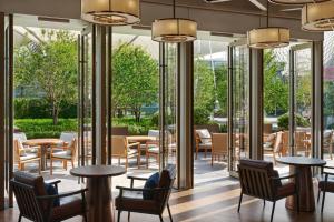 a restaurant with tables and chairs and windows at Thompson Shanghai Expo, by Hyatt in Shanghai