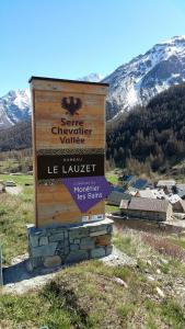 a sign in a field with mountains in the background at chez Annie & Marcel in Le Monêtier-les-Bains