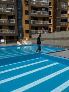 a person walking in front of a swimming pool at JK properties in Kampala