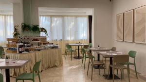 a dining room with tables and green chairs at Hotel Abay in Rimini
