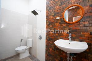 a bathroom with a toilet and a sink and a mirror at Griya Borobudur Malang Syariah RedPartner in Blimbing +35 photos
