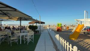 a restaurant with people sitting at tables and a playground at Hotel Abay in Rimini