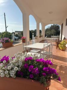 a patio with purple and white flowers and a table and chairs at Mater in Capilungo