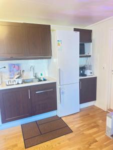 a kitchen with brown cabinets and a white refrigerator at Cozy 2-Bedroom Apartment in Kristiansand