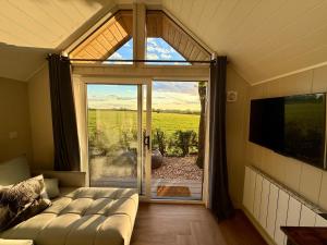 a living room with a couch in front of a sliding glass door at Rhosyn Highland Cattle Farm in Dunstall