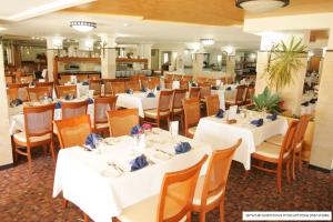 a dining room with white tables and chairs at Ron Beach Hotel in Tiberias