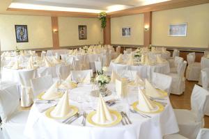 ein Raum voller Tische mit weißen Tischeinstellungen in der Unterkunft Hotel Alt Riemsloh in Melle