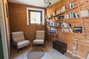a room with two chairs and shelves of books at Les Greniers in Myon