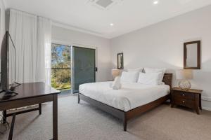 a bedroom with a bed and a desk and a television at Surfside in East Ballina