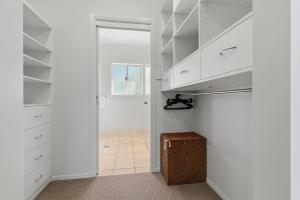 a walk in closet with white cabinets and a doorway at Surfside in East Ballina +27 photos