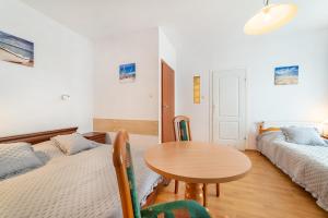 a room with two beds and a wooden table at Willa Promyk in Jastarnia