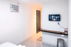 a room with a tv on a white wall at Graha Martadinata Syariah Mitra RedDoorz in Tasikmalaya +16 photos
