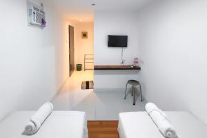 a white room with two beds and a tv at Graha Martadinata Syariah Mitra RedDoorz in Tasikmalaya