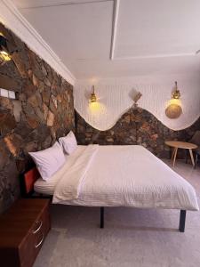a bed in a room with a stone wall at Balcony walk rest house Jabal shams in Sa‘ab Banī Khamīs