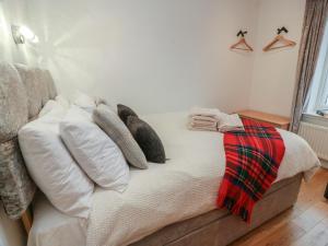 a bed with a pile of pillows on it at Rosalin Cottage in Irvine
