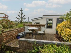a wooden deck with a table and chairs on it at Rosalin Cottage in Irvine