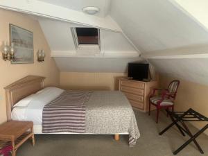 a bedroom with a bed and a tv and chairs at Hôtel Chandouineau in Redon