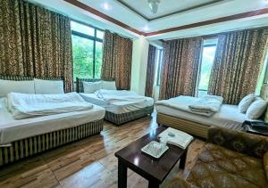 ein Wohnzimmer mit zwei Betten und einem Tisch in der Unterkunft New Islamabad Hotel in Islamabad