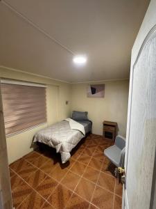 a bedroom with a bed and a window and a chair at Hostel Campus Lircay in Talca