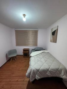 a bedroom with a bed and a chair in it at Hostel Campus Lircay in Talca