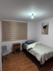a bedroom with a bed and a window with a chair at Hostel Campus Lircay in Talca