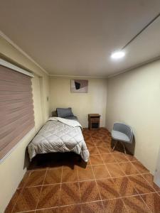 a bedroom with a bed and a chair in it at Hostel Campus Lircay in Talca