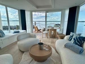a living room with white furniture and large windows at Fleesensee Resort & Spa in Göhren-Lebbin