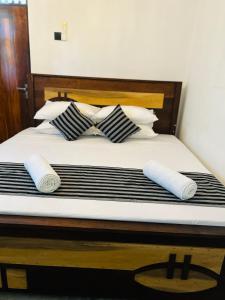 a bedroom with a bed with black and white pillows at jungle view in Nilwella