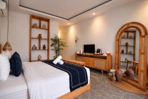 a bedroom with a bed and a desk and a television at Penida Green Palm Cottage in Nusa Penida