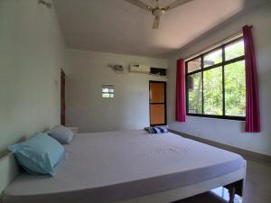 a bedroom with a large bed with a window at Rooms In Canacona in Canacona