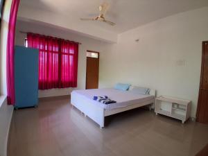 a bedroom with a white bed and a red window at Rooms In Canacona in Canacona