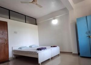 a bedroom with a white bed and a blue door at Rooms In Canacona in Canacona