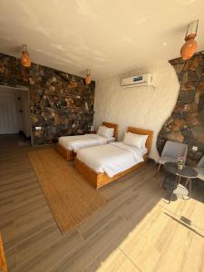 a bedroom with two beds and a stone wall at Panorama Guest House Jabal Shams in Sa‘ab Banī Khamīs