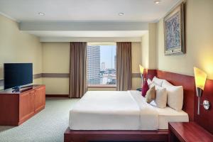 a hotel room with a bed and a television at Mercure Jakarta Kota in Jakarta