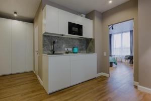 a kitchen with white cabinets and a living room at Вікторі Апарт in Kyiv