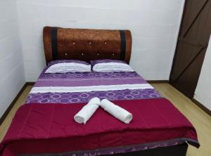 a purple bed with two white towels on it at SELAMA Merdeka Homestay 2-6pax in Selama