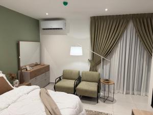 a bedroom with a bed and two chairs and a mirror at Luxury Aestethics at Bantree in Accra +12 photos
