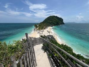 a view of a beach with a fence and the ocean at Palm Garden Resort in Carles
