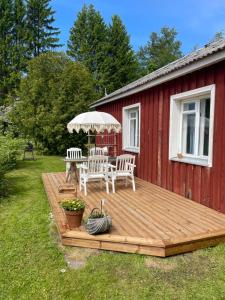 a deck with a table and chairs and an umbrella at Aabu Maja in Kõrgessaare
