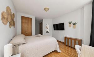 a white bedroom with a bed and a tv at The NYC Value Room near Times Square & Broadway - Private Room with shared bathroom in New York