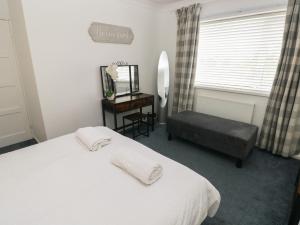 a bedroom with a bed and a chair and a mirror at Cwtch Ar Y Mor in Burry Port